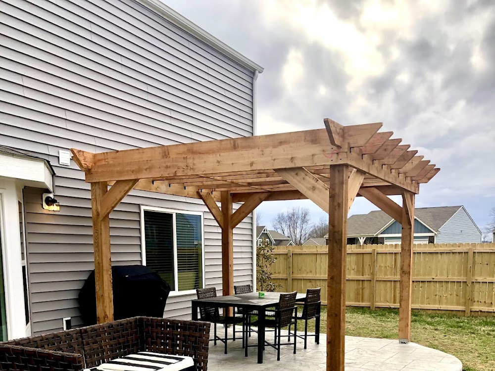 A finished cedar pergola standing over a patio area in a back yard.