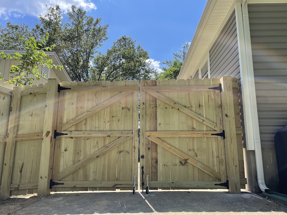 A tall wooden double privacy gate across a driveway, closed and squared to the fence line.